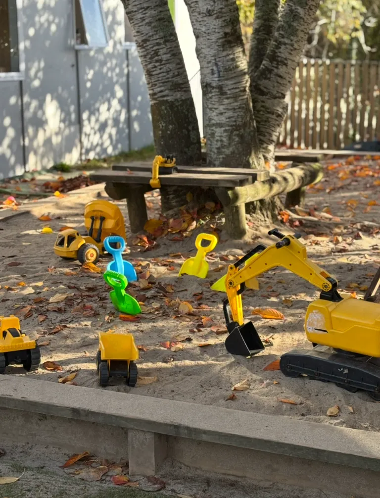 Tamariki digging with diggers and trucks in the sandpit